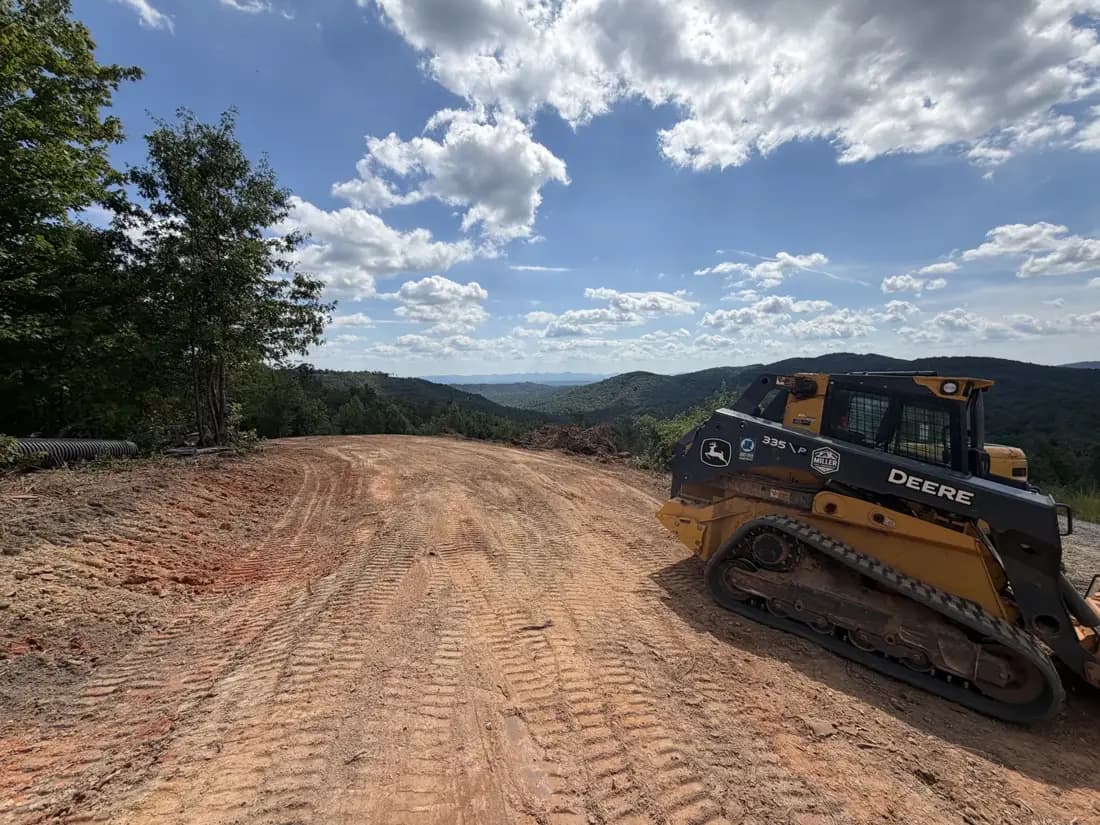 John Deere track loader grading a new gravel driveway with a mountain view